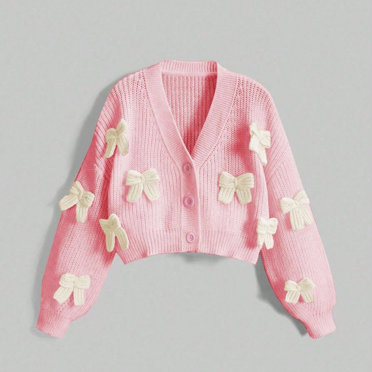 Pink cardigan with butterfly embellishments on a gray background