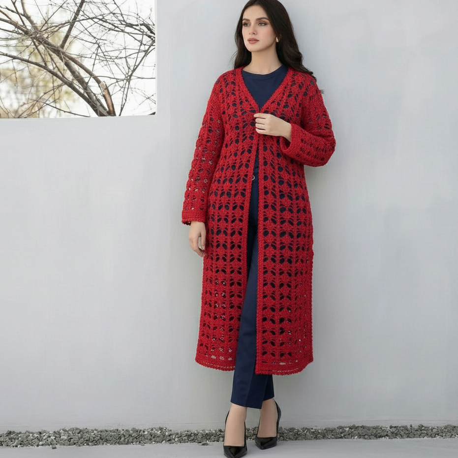Woman wearing a long red patterned coat against a white wall.