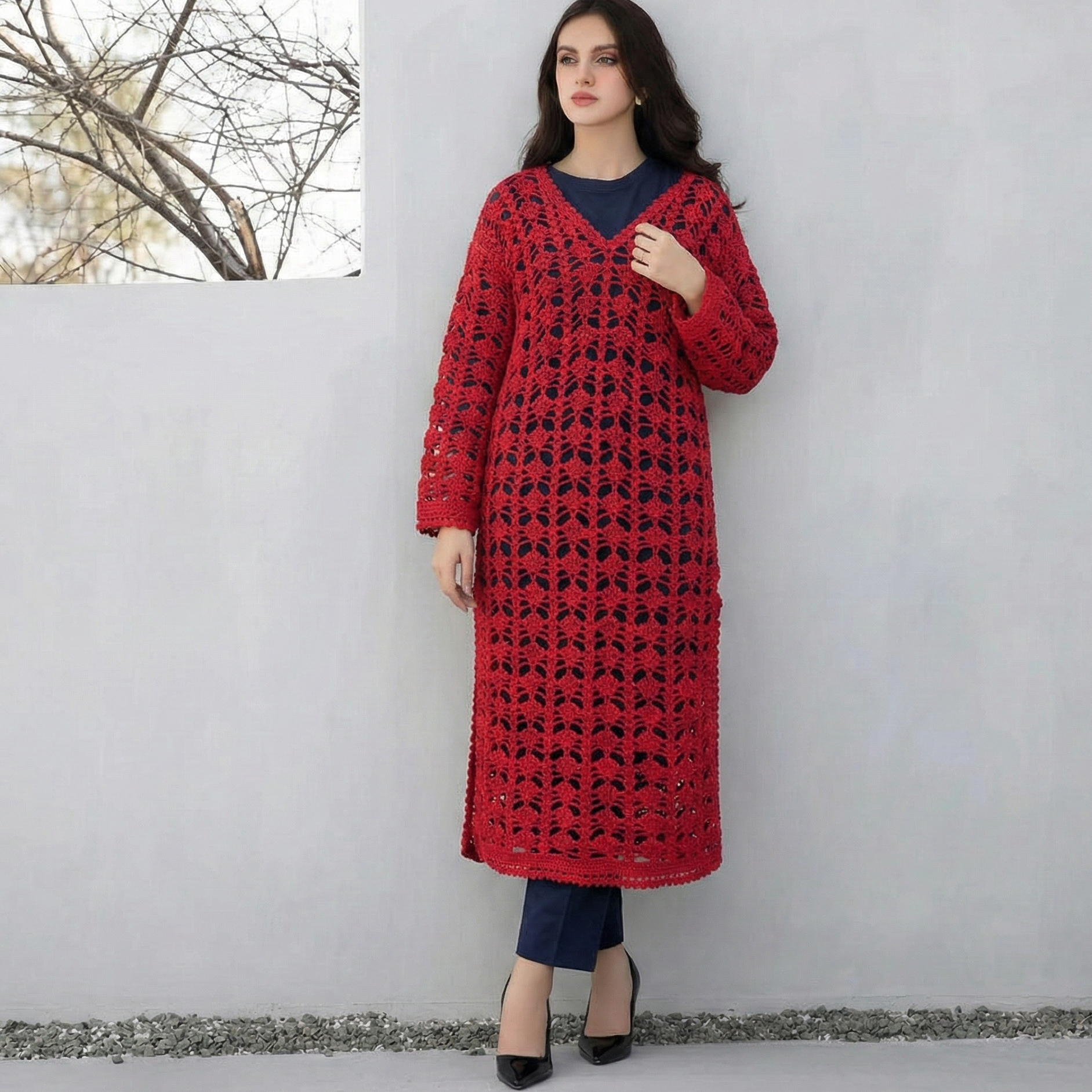 Woman wearing a red crochet dress against a white wall