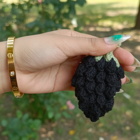 Hand holding a blackberry with a blurred green outdoor background