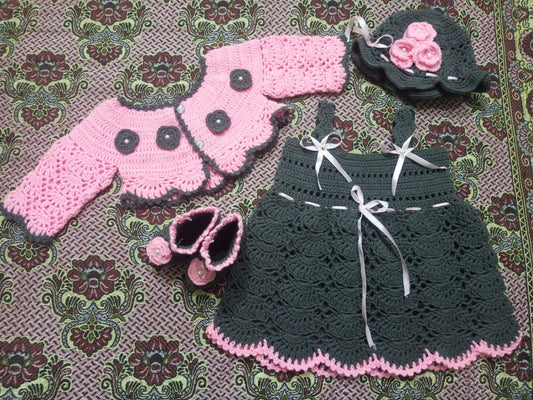 Crocheted black and pink baby outfit on a patterned fabric background